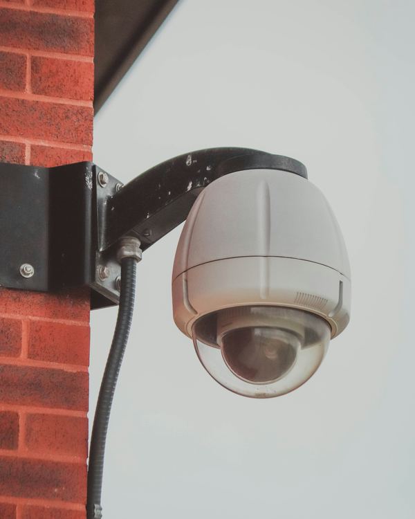 A dome security camera mounted on the brick exterior wall of a building