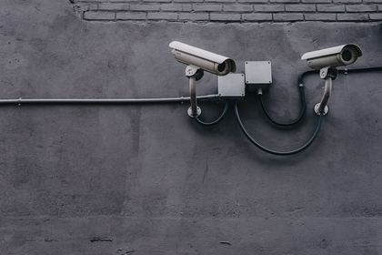 Two outdoor bullet cameras mounted on a wall, wired back through a single conduit