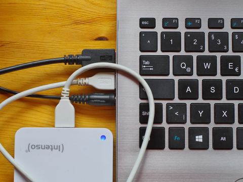 An external backup drive plugged into a laptop on a desk