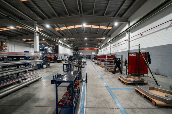 The inside of a working manufacturing plant with benches and materials down a long aisle
