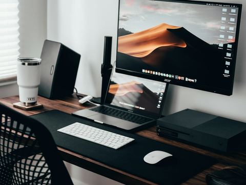 A tidy home office desk with a monitor, laptop and keyboard