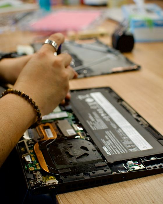 A laptop opened up on a workbench with its internal parts exposed during a repair