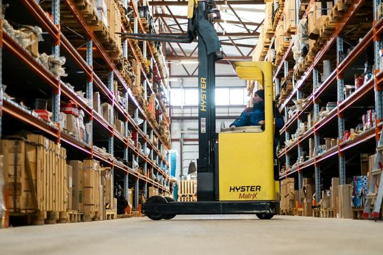 A forklift in the aisle of a stocked distribution warehouse